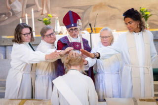 Piispa ja avustajat siunaamassa vihittyä