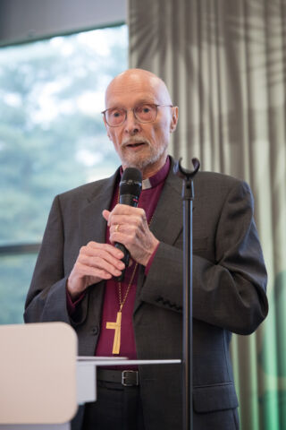 Piispa emeritus Juha Pihkala pitelee mikrofonia ja pitää puhetta synodaalikokouksessa 2023.